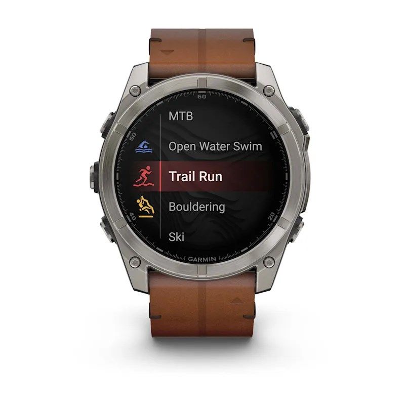 Garmin Fenix 8 AMOLED 51 mm-es okosóra barna szíjjal, elölnézetből, a kijelzőn sportágválasztó menüvel és kiemelt terepfutás móddal.