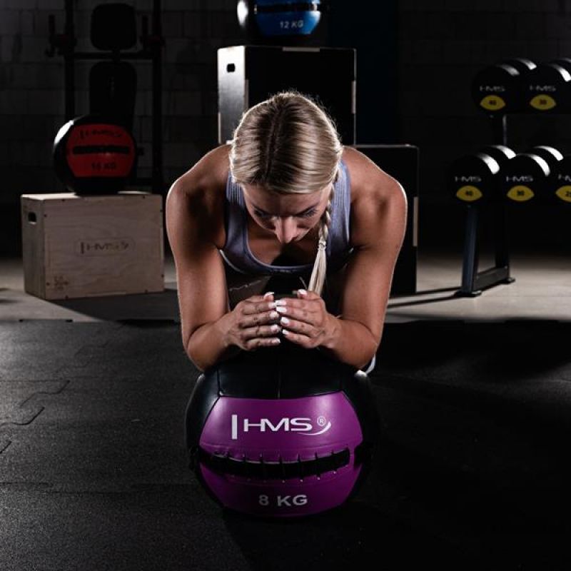 Női sportoló törzserősítő plank gyakorlatot végez HMS wall ball medicinlabdával edzőteremben