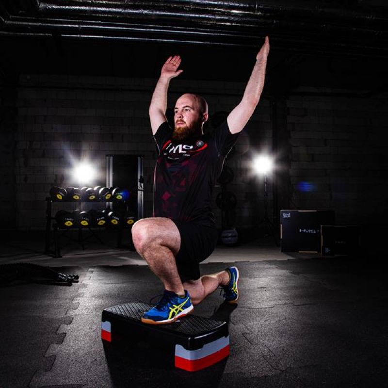 Sportoló kitörés gyakorlatot végez állítható fitness step platformon, funkcionális egyensúlyfejlesztő edzés közben
