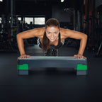 Női sportoló fekvőtámaszt végez állítható fitness step platformon edzőtermi környezetben
